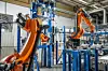 Oransje industrikroboter arbeider i en moderne fabrikkhall.