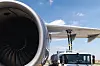 Nærbilde av flymotor og vingeparti mens tankbil fyller drivstoff på flyet ved gate.