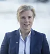 Portrett av ei kvinne i blå blazer mot lys bakgrunn.
