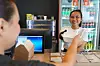 To personer jobber i en takeawaydisk med matbokser, kjøledisk og kasse i et lite serveringslokale.