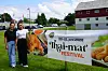 To kvinner står ved siden av et banner for Thai-mat Festival på gresset foran en bygning.