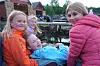 Fire barn sitter tett sammen ved vannet og ser mot en havn med båter og bygninger i bakgrunnen.