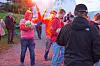 Folk står på en strand med flammer og røyk i bakgrunnen, mens flere filmer med mobil.