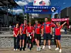 En gruppe norske supportere står foran et stadionområde med banner, flagg og rødt Norge-skilt.