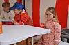 Tre barn sitter ved et hvitt bord inne i et rødhvitt telt.