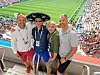 Fire menn står sammen foran en fullsatt fotballarena med grønt gress og tribuner i bakgrunnen.