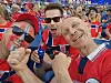 Tre norske supportere sitter tett sammen på en stadion og jubler med rødt og blått ansiktsmaling.