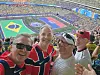 Fire menn tar en selfie på tribunen med et stort, fullsatt stadion i bakgrunnen.