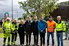 En gruppe voksne og barn står samlet utendørs ved en ny lekeplass.