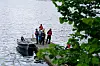 En liten gruppe står på en brygge ved vannet med en båt fortøyd ved siden av.