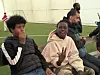 Barn og voksne sitter på tribunen ved en innendørs fotballbane.