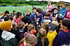 En gruppe barn står tett rundt en fotballspiller på en gressbane og får autografer.