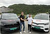 To servicebiler står side om side på en grusplass foran skogkledde fjell.