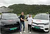 To servicebiler står side om side på en grusplass foran skogkledde fjell.