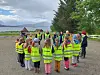 En gruppe barn og voksne står i ring utendørs på en gårdsplass.