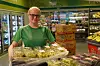 En person i grønn Kiwi-uniform holder en stor kurv med druer i en dagligvarebutikk.