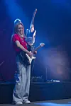 Gitarist spiller elektrisk gitar på en scene med blått lys og røyk.