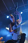 Gitarist spiller elektrisk gitar på scene med blått lys og røyk.