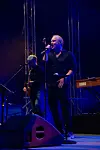 Vokalist synger på en blå scenen med musiker og Korg-tangentbord ved siden av.