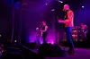 Rockeband spiller på scene med lilla lys og instrumenter.