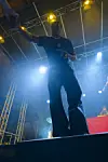 En artist står på en opplyst scene med blått lys og lysrigg i bakgrunnen.