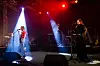 Band opptrer på en scene med rødt lys og sterke lyskastere.