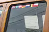 Nærbilde av vindu på en eldre buss med små flagg klistret øverst.
