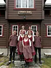 Seks personer står samlet foran inngangen til Reindalseter, en brun fjellhytte med skilt over døren.