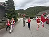 Flere barn i røde klær står og løper på en grusvei med norske flagg og hus i bakgrunnen.
