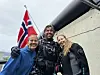 Tre personer står tett sammen og smiler foran et fly med et norsk flagg.