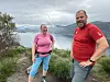To personer står på en sti med fjord og by i bakgrunnen.