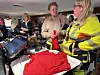 Folk står ved en disk i en sportsbutikk med røde trøyer, en kassaskjerm og klær i hyllene i bakgrunnen.