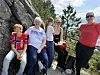 Fem personer sitter og står på svaberg med trær og himmel i bakgrunnen.