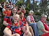 En gruppe mennesker i røde drakter sitter på steintrappene utendørs, noen holder skjerf og andre tar bilder.