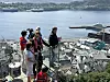 Flere personer står på en trapp med utsikt over en havn og fjord i sollys.