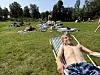 En gutt ligger tilbakelent i en stol på en gressbakke mens flere personer soler seg i bakgrunnen.