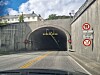 En bil kjører mot en mørk tunnelinnkjøring med skilt på begge sider. Tunnel. Valderøytunnelen. Ellingsøytunnelen.