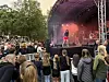 Et stort publikum ser på en artist som står på en utendørsscene med røyk og lys.
