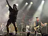 Et rockeband opptrer på en scene med kraftige lys og et trommesett i bakgrunnen.