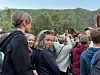 En folkemengde ser mot en scene utendørs med grønne åser i bakgrunnen.