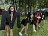 Store svarte bokstaver står på gresset i en park med trær i bakgrunnen, mens flere personer står bak og mellom bokstavene.