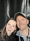 En ung kvinne og en mann tar en selfie foran en mørk, blank bakgrunn.