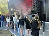 Barn og voksne står ved gjerde foran en utendørsscene med røyk og rødt lys.