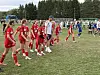 Ungdomsspillere i rødt og blått står samlet på en gressbane før eller under kamp.