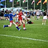 To ungdomsspillere i rød og blå drakt kjemper om ballen på en fotballbane.