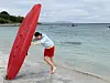 Person holder et stort rødt redningsbrett i vannkanten på en strand.
