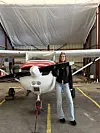Kvinne står foran et lite propellfly i en hangar.