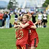 To Spjelkavik-spillere i røde drakter klemmer hverandre på en fotballbane med publikum i bakgrunnen.
