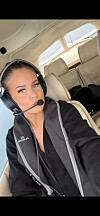En kvinne med headsett sitter i cockpit i et lite fly med beige seter.