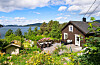 Enebolig med terrasse og frodig hage med utsikt mot fjorden og øyer i bakgrunnen.